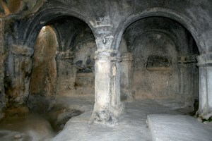 Decorated support columns hold up a soot blackened roof in one of the many enclaves.  To the left, a drain that would have carried away water and maybe blood from sacrificial animals.